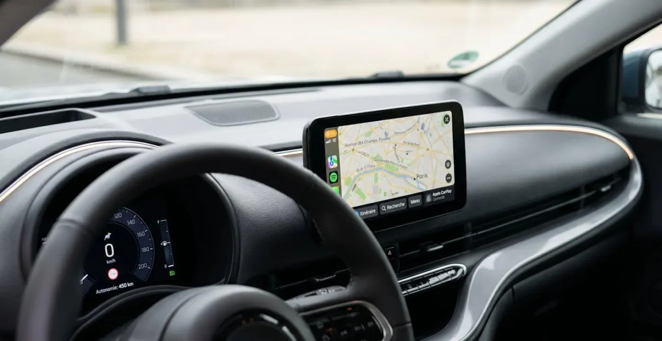 Tableau de bord moderne de citadine avec écran tactile central de 8 pouces affichant une carte de navigation de Lyon et interface Apple CarPlay, volant et instrumentation numérique visibles